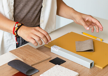 Student housing FF&E material samples being examined by a designer | Turnkey FF&E & Interiors | The Living Company | Garland, Texas