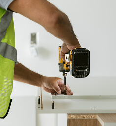 Student housing kitchen cabinet installer using a drill | Turnkey FF&E & Interiors | The Living Company | Garland, Texas